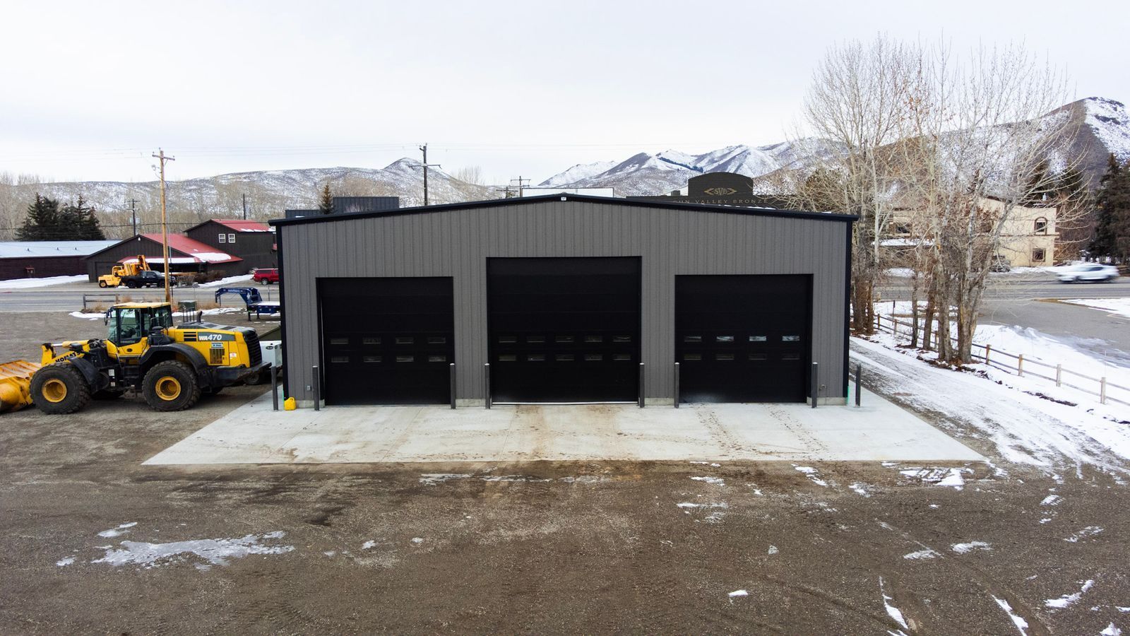 An aerial view of a garage with a snow plow parked in front of it.