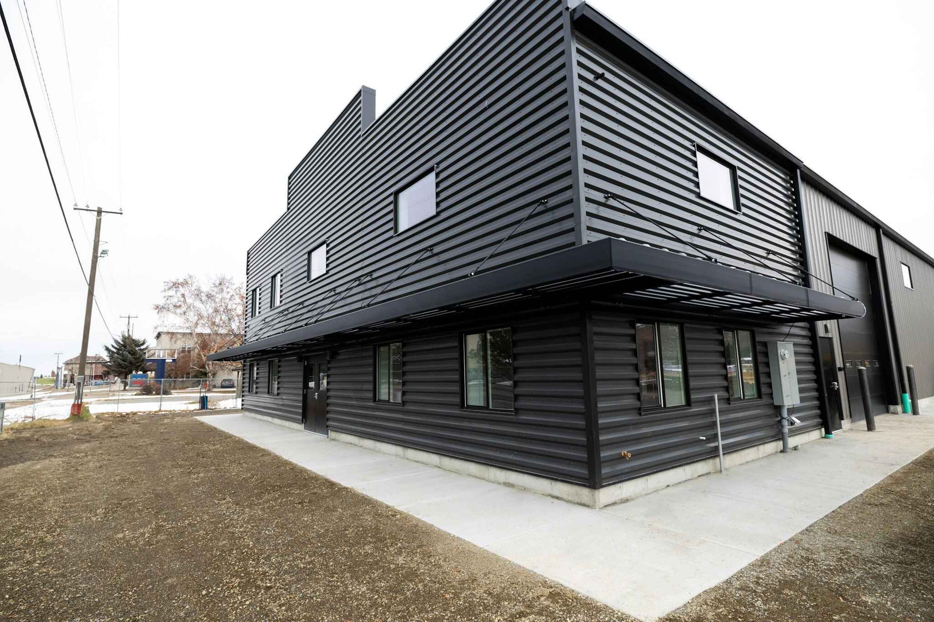 A large black building with a lot of windows is sitting on top of a dirt field.