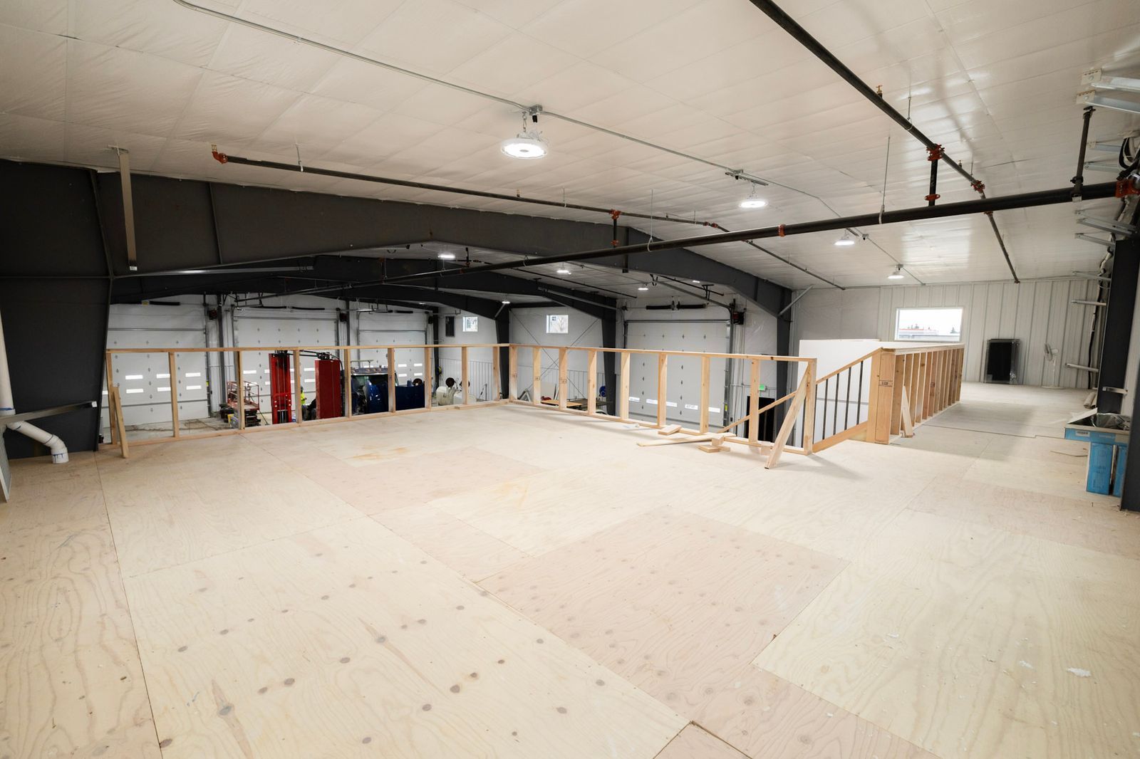 A large empty warehouse with a wooden floor and stairs.