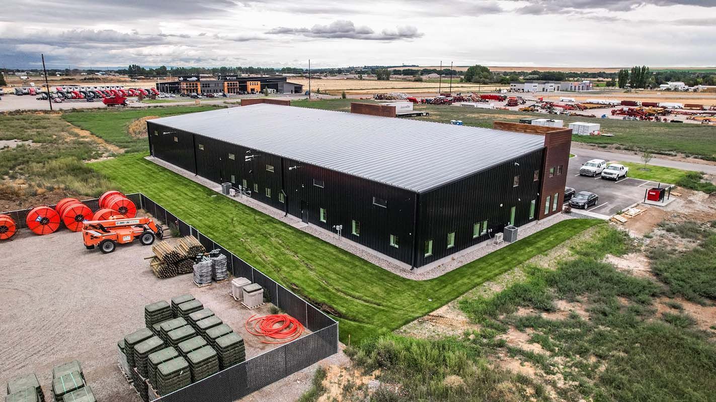 Black warehouse with a metal roof in an open field
