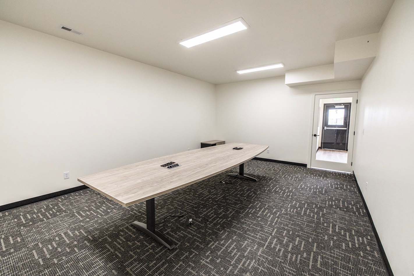 Empty office room with a long conference table, carpet, and open doorway