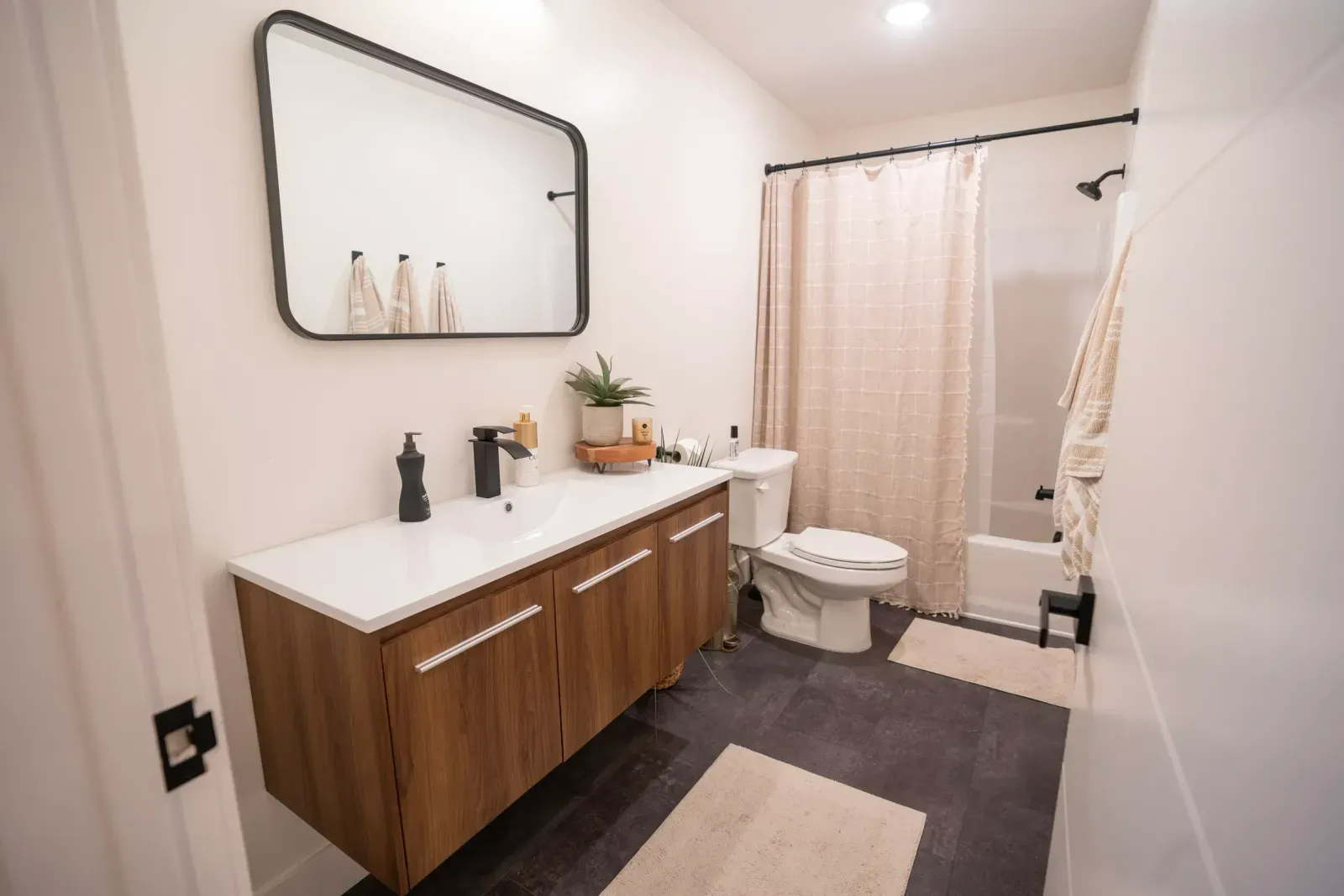 A bathroom with a sink , toilet , shower and mirror.