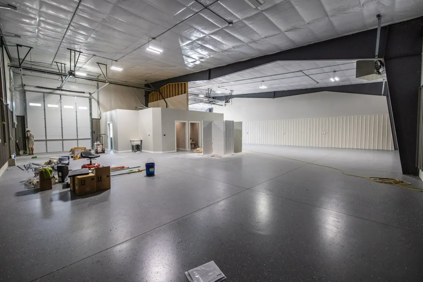 A large empty room with a lot of windows and boxes on the floor.