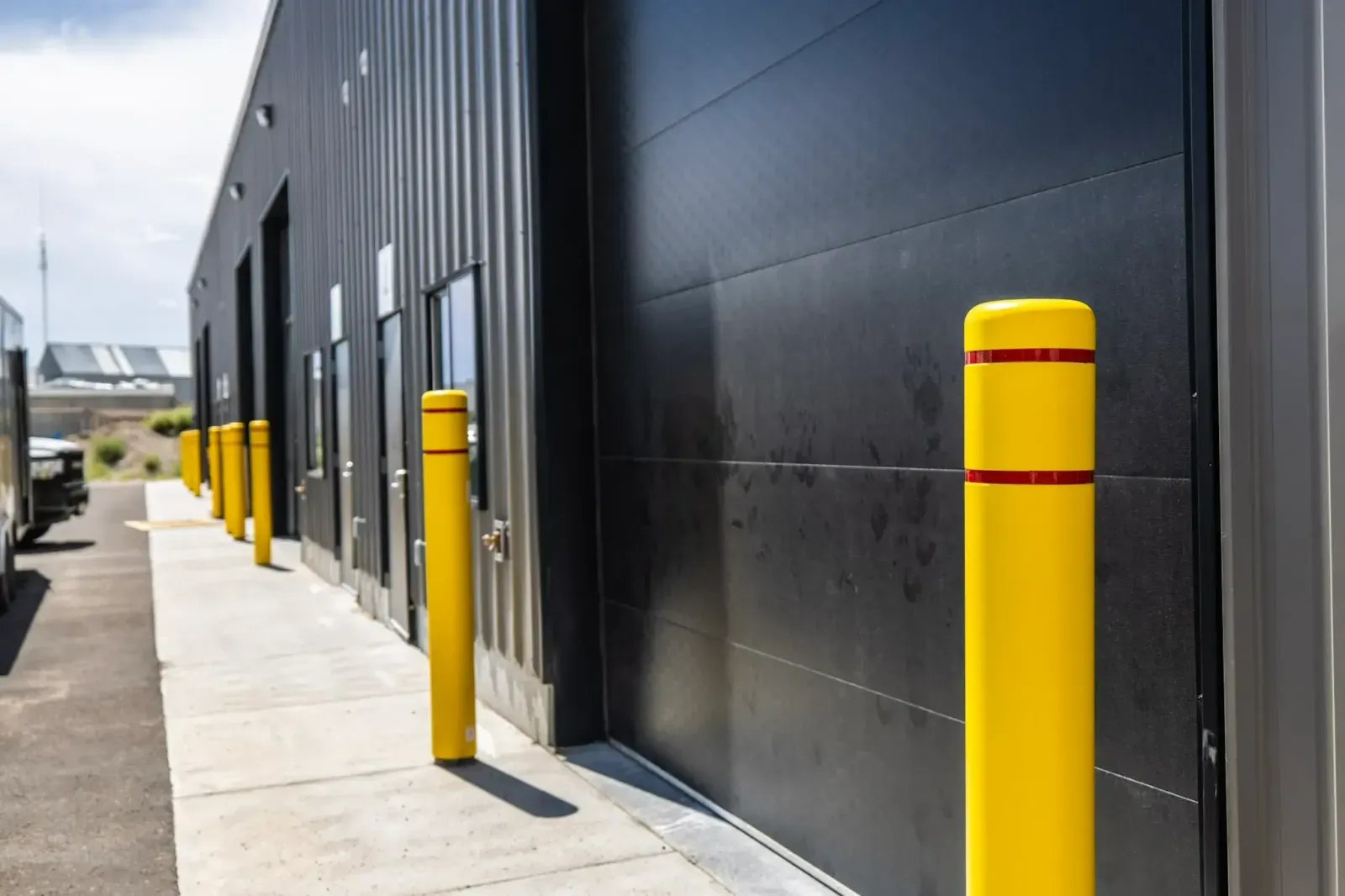 A row of yellow poles are lined up in front of a building.