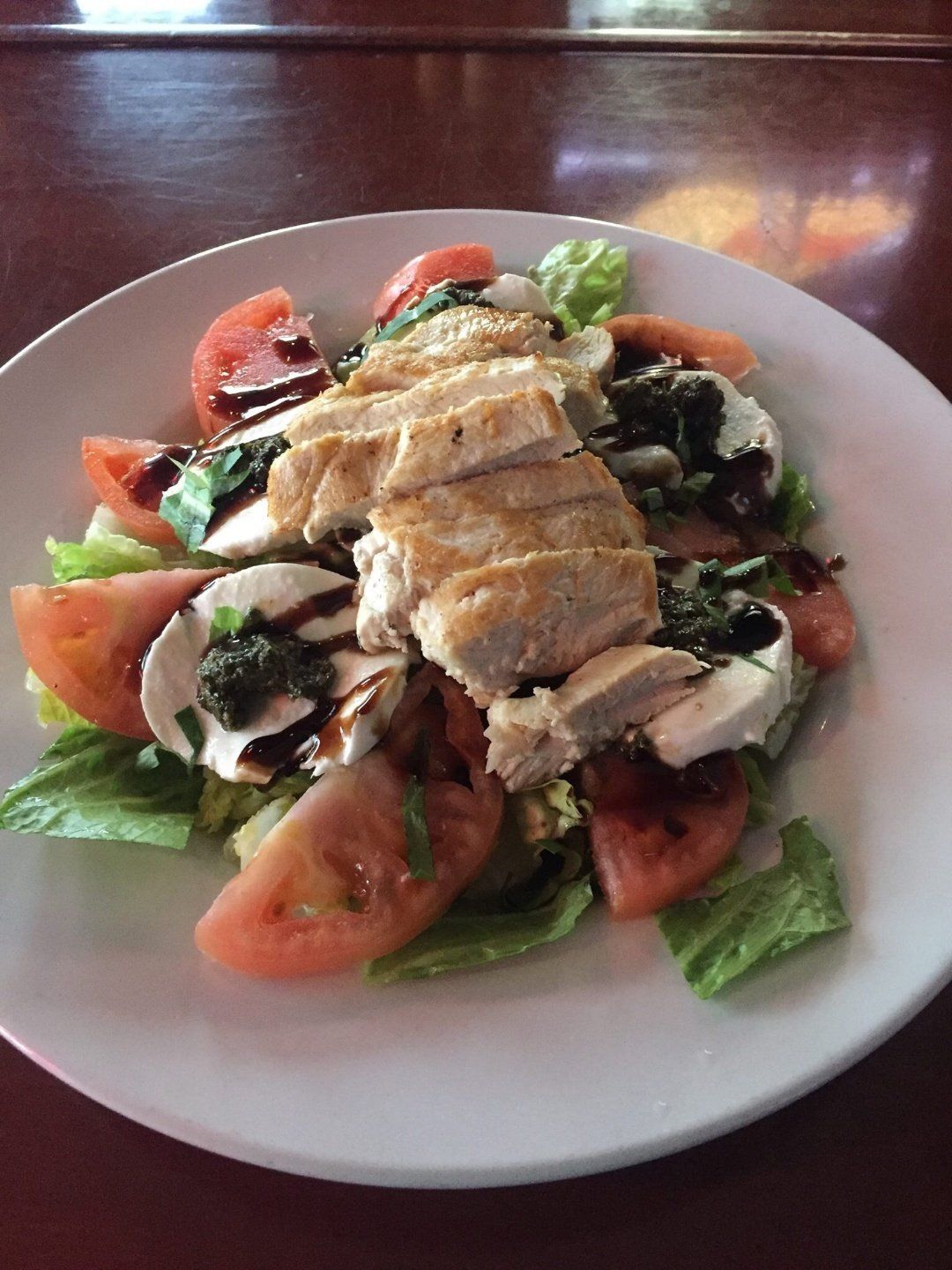 A white plate topped with a salad of chicken , tomatoes , lettuce and mushrooms.