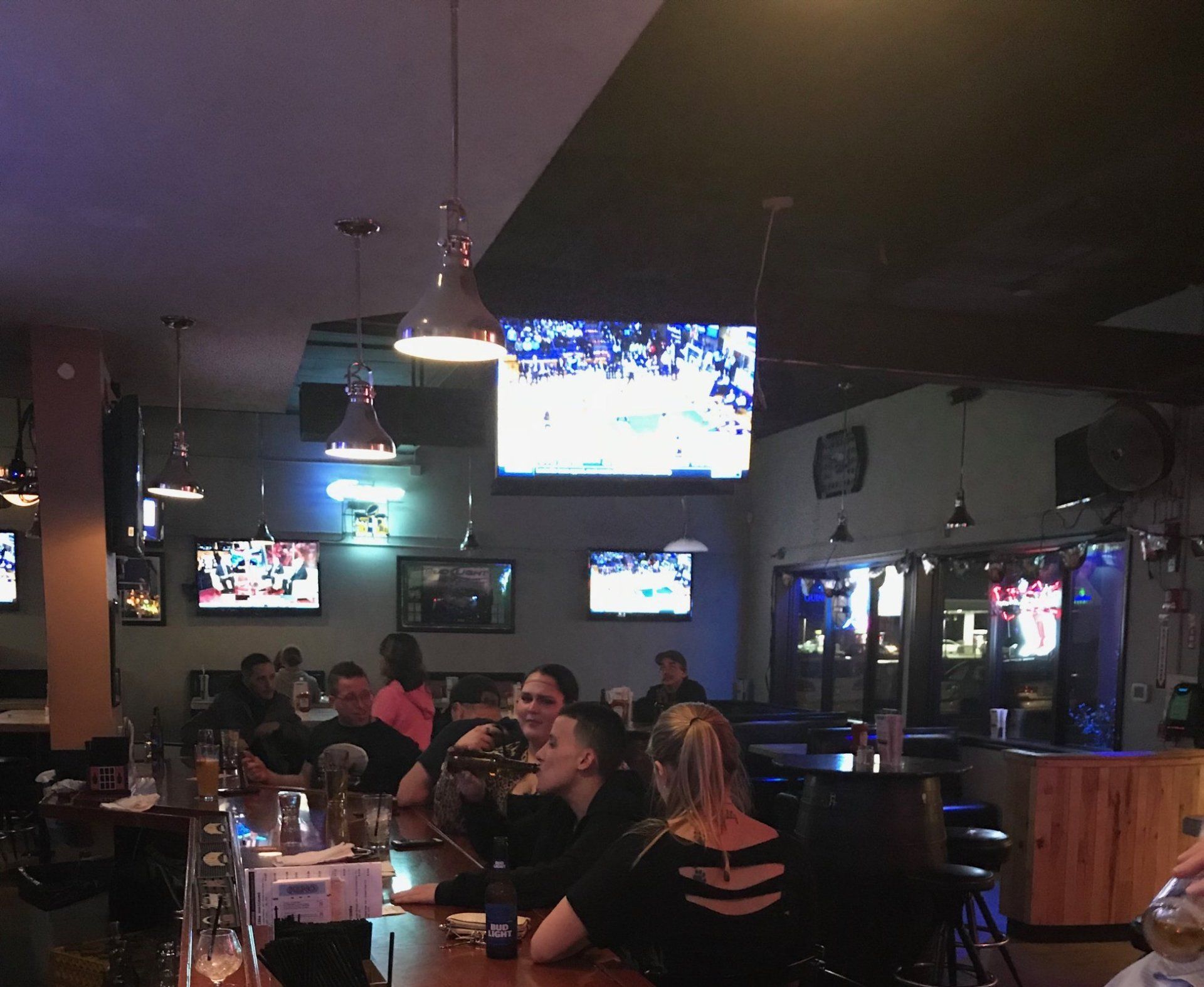 A group of people are sitting at tables in a restaurant watching a game