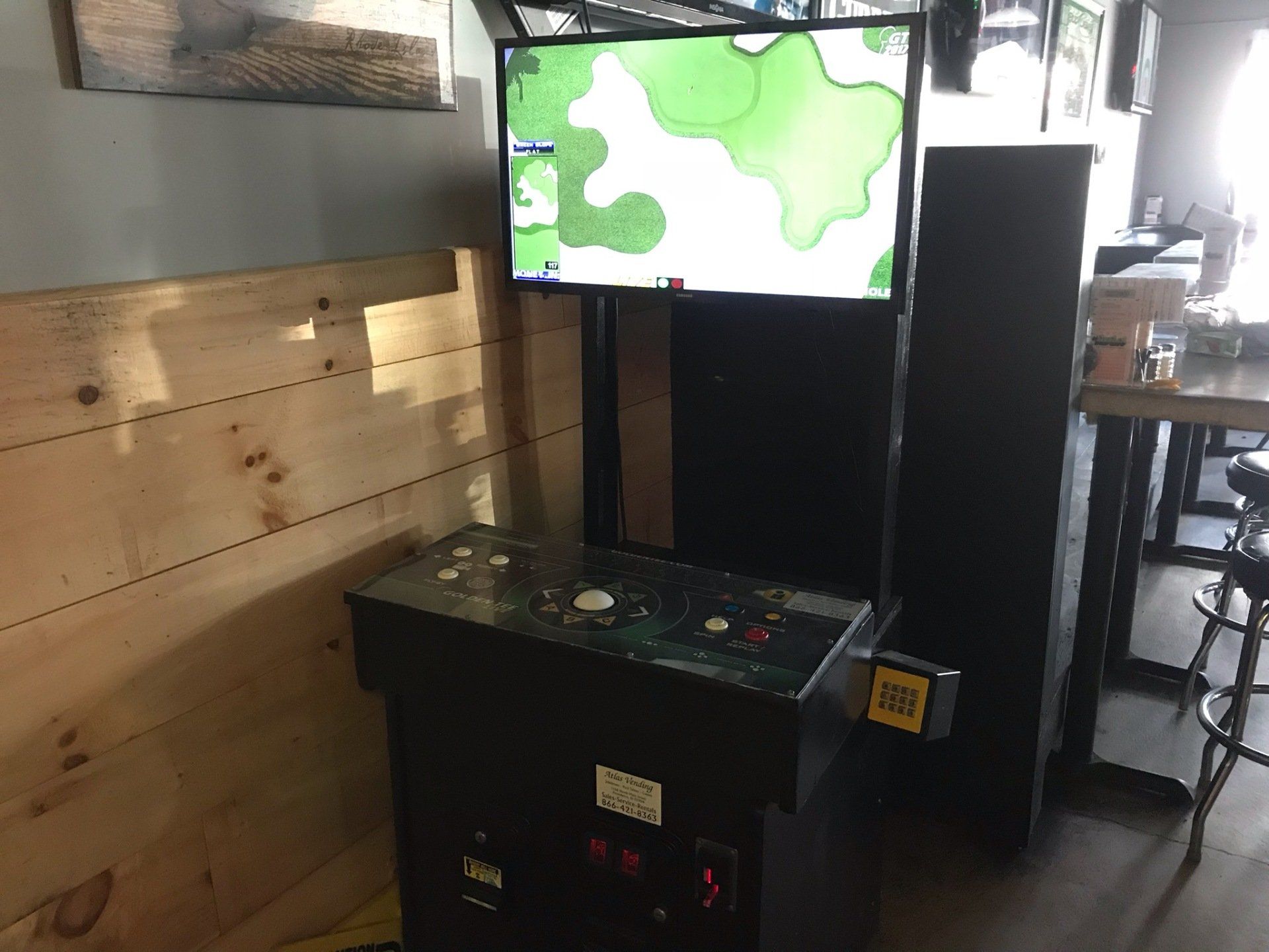 A video game machine is sitting in a room next to a wooden wall.