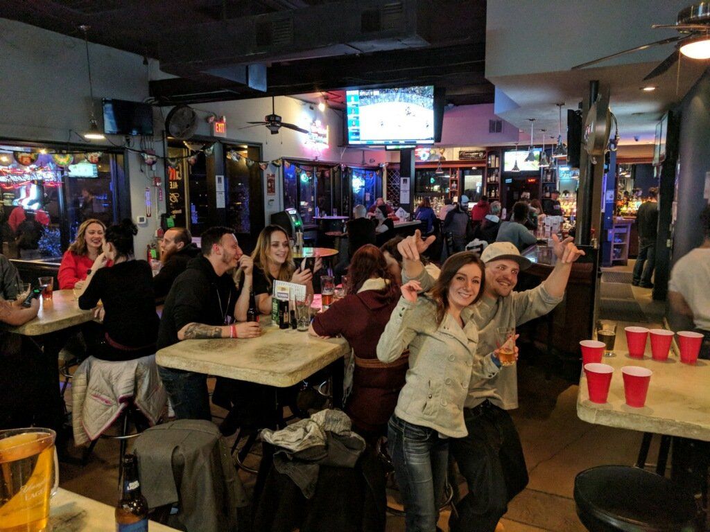 A group of people are sitting at tables in a bar.