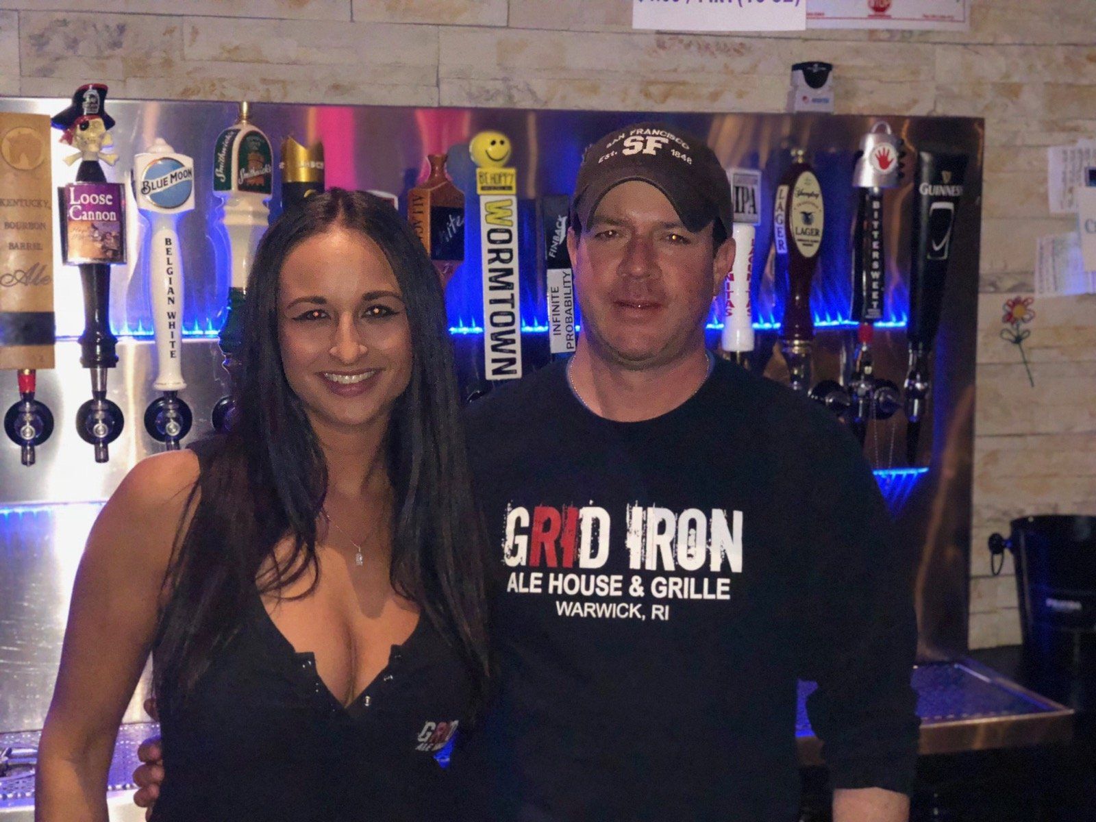 A man and a woman are posing for a picture at grid iron ale house and grille
