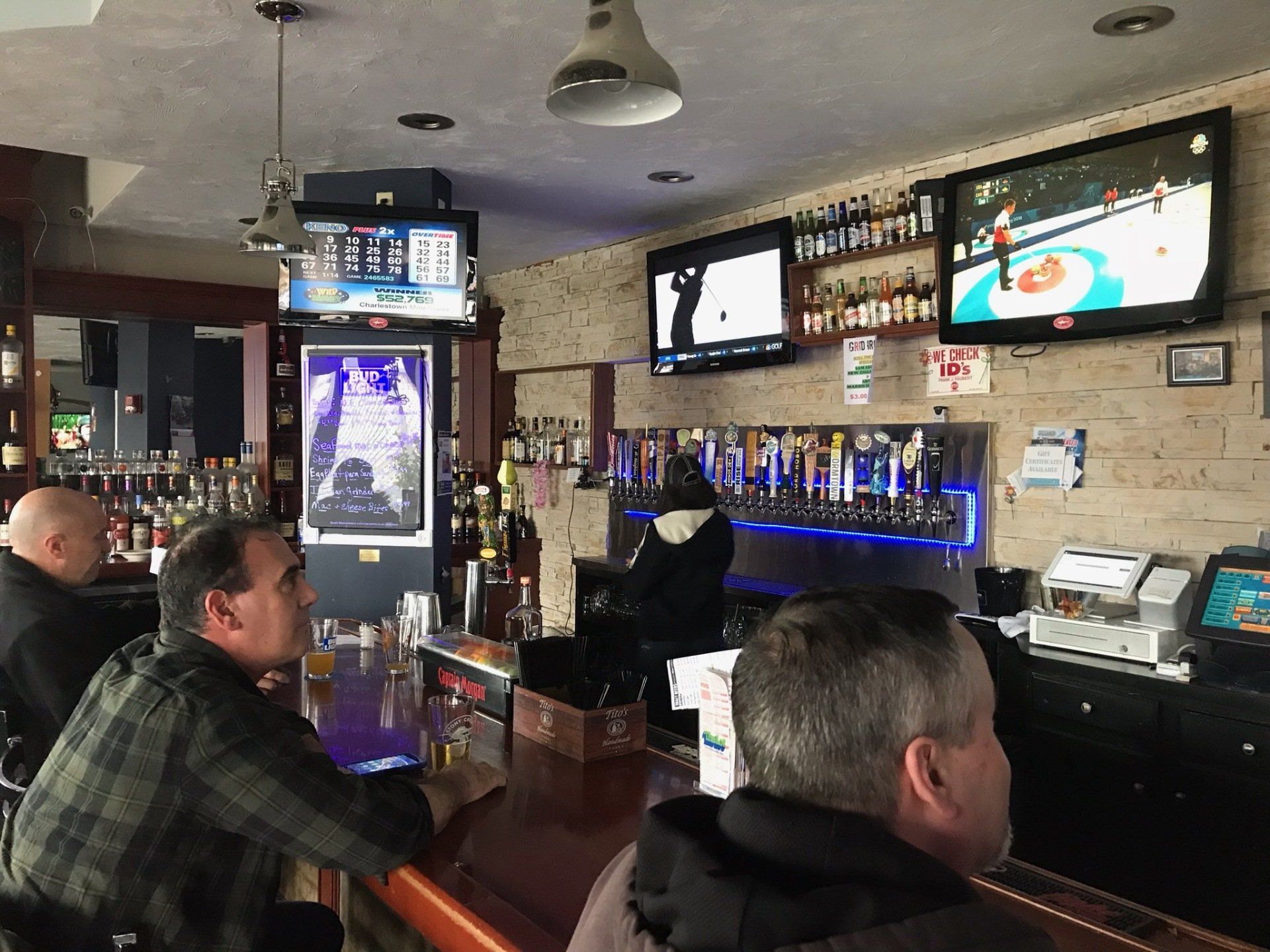 A group of men are sitting at a bar watching a hockey game.