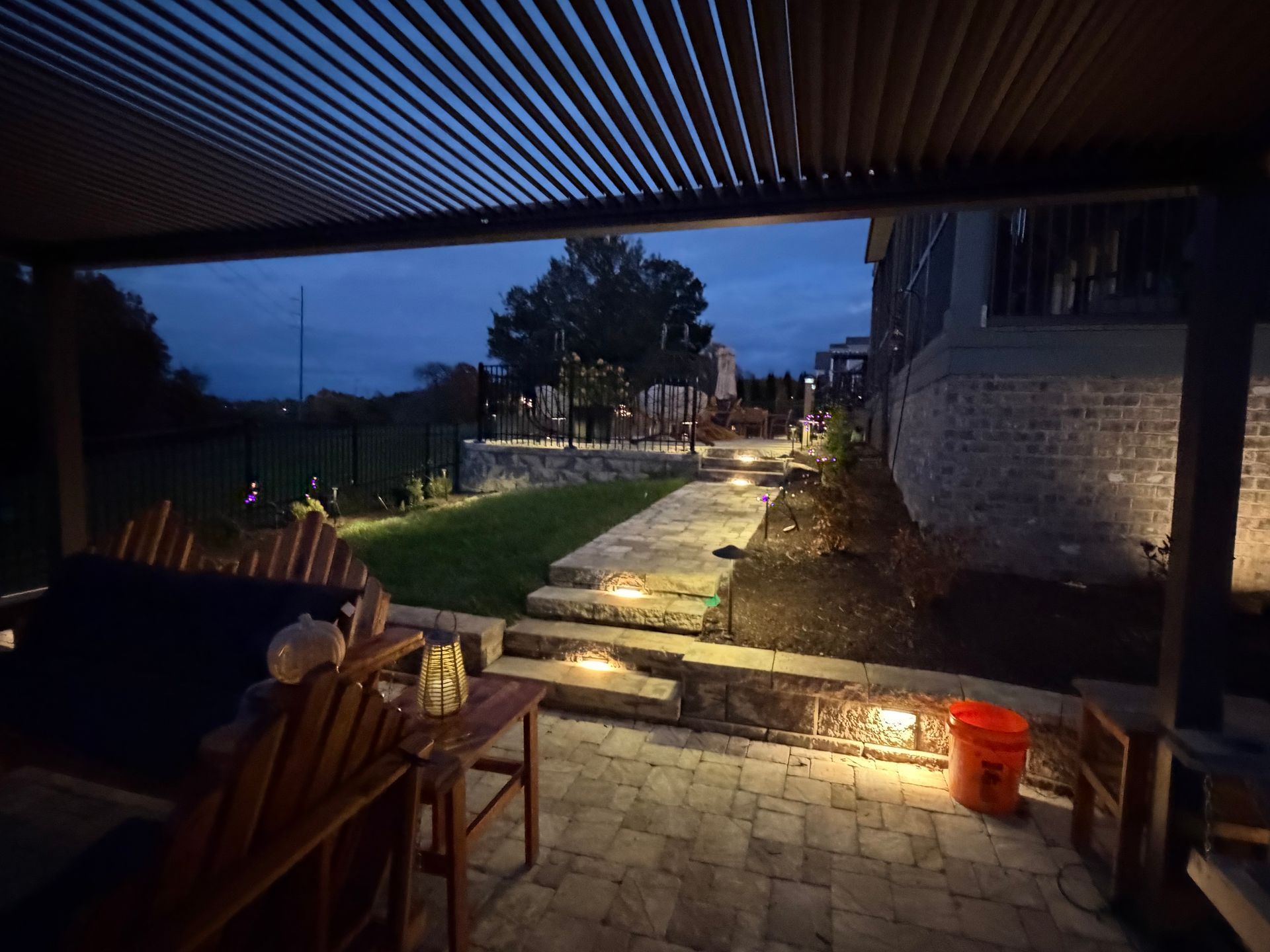 Outdoor patio with pergola and landscape lighting at dusk.