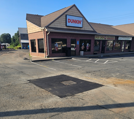 Dunkin’ storefront with parking lot and a curb ramp on a sunny day