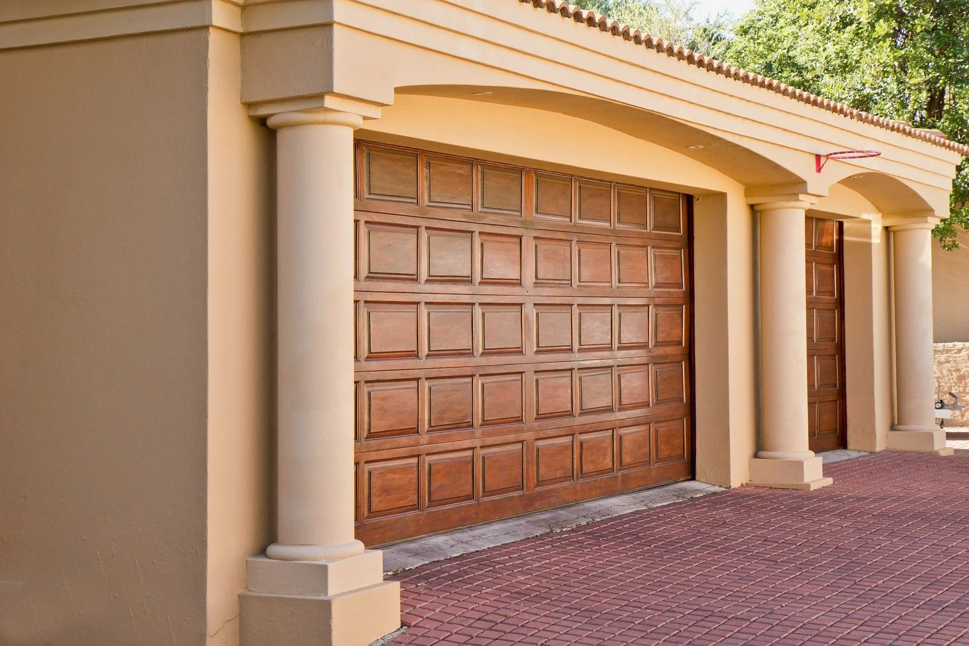 Closed brown garage door on a beige stucco house with a tiled roof and gravel driveway