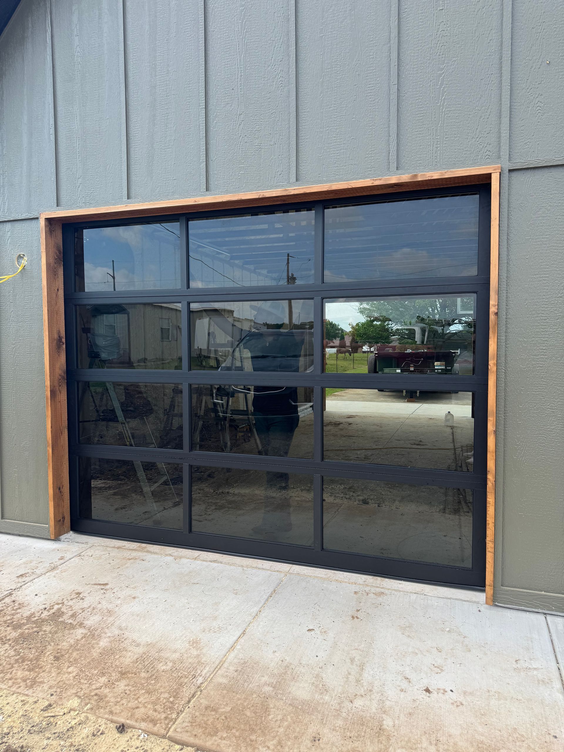 Black-framed glass storefront door set in a gray corrugated wall with a concrete sidewalk.