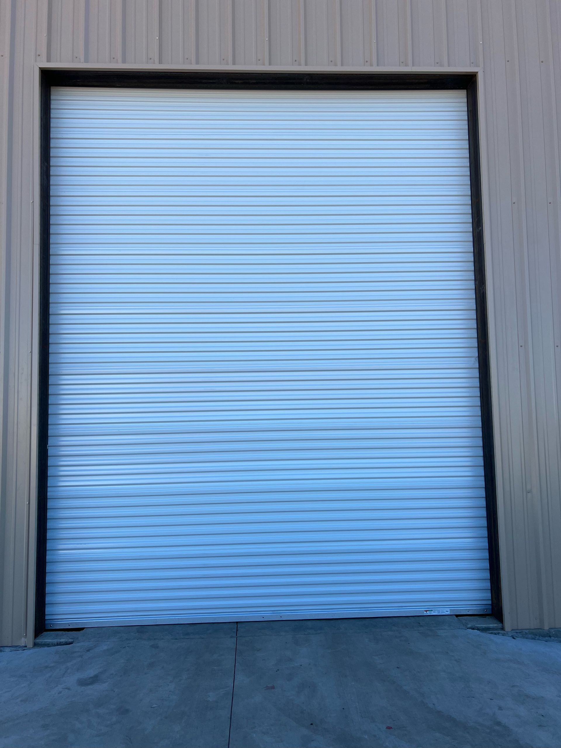Blue roll-up warehouse door in a gray corrugated metal wall