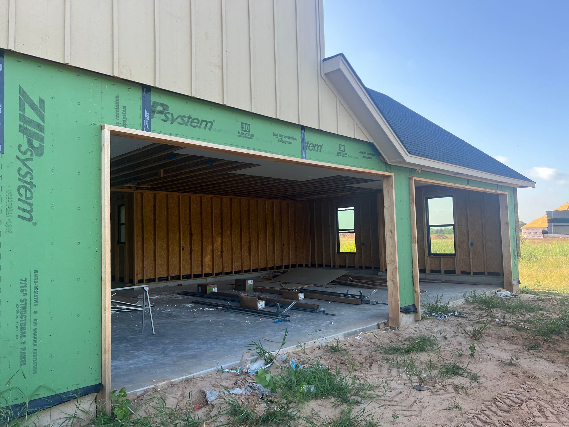 Partially built house with open garage-like frame, green siding, and unfinished interior.