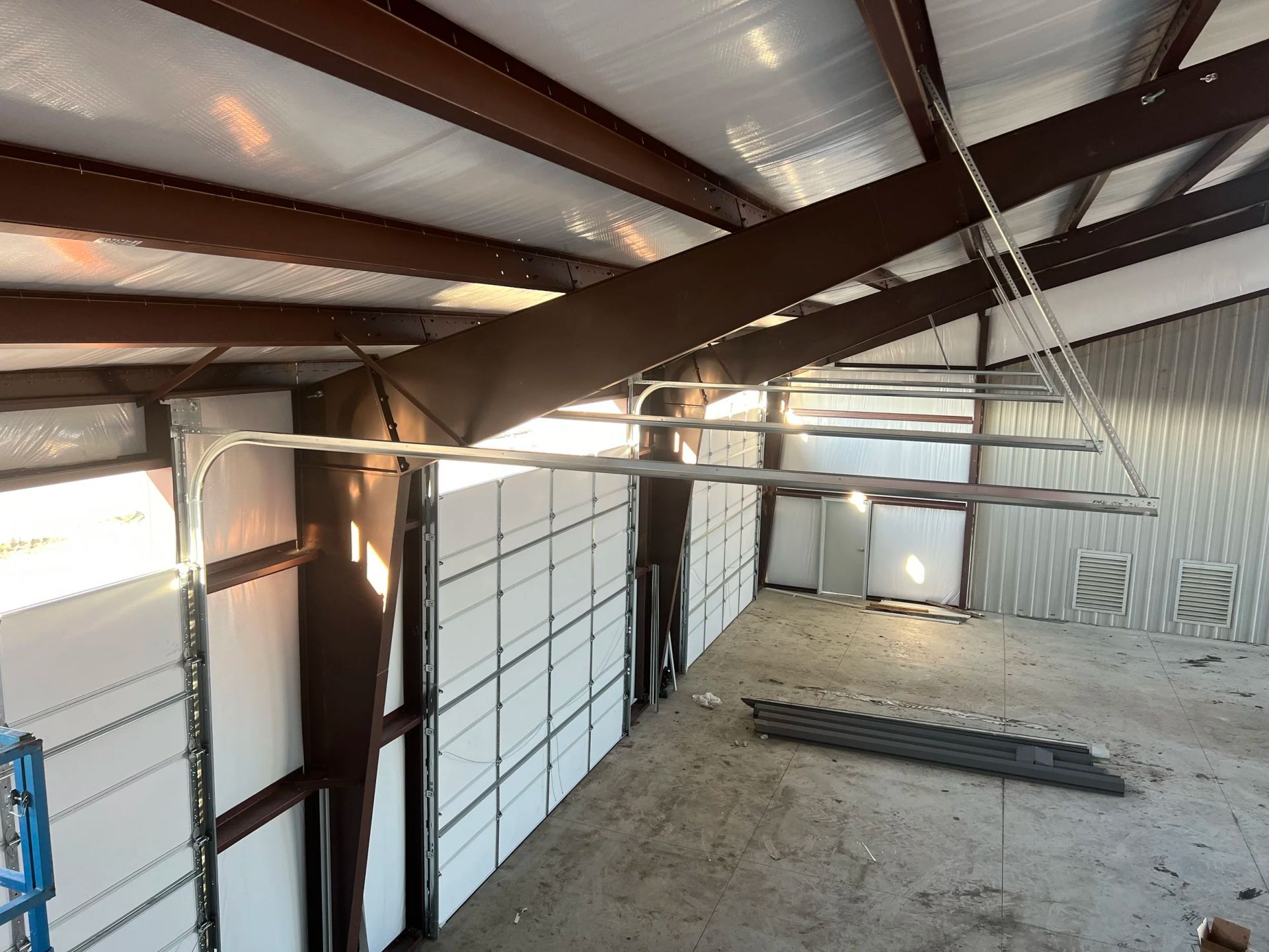 Empty metal warehouse interior with exposed beams, roll-up doors, and a concrete floor