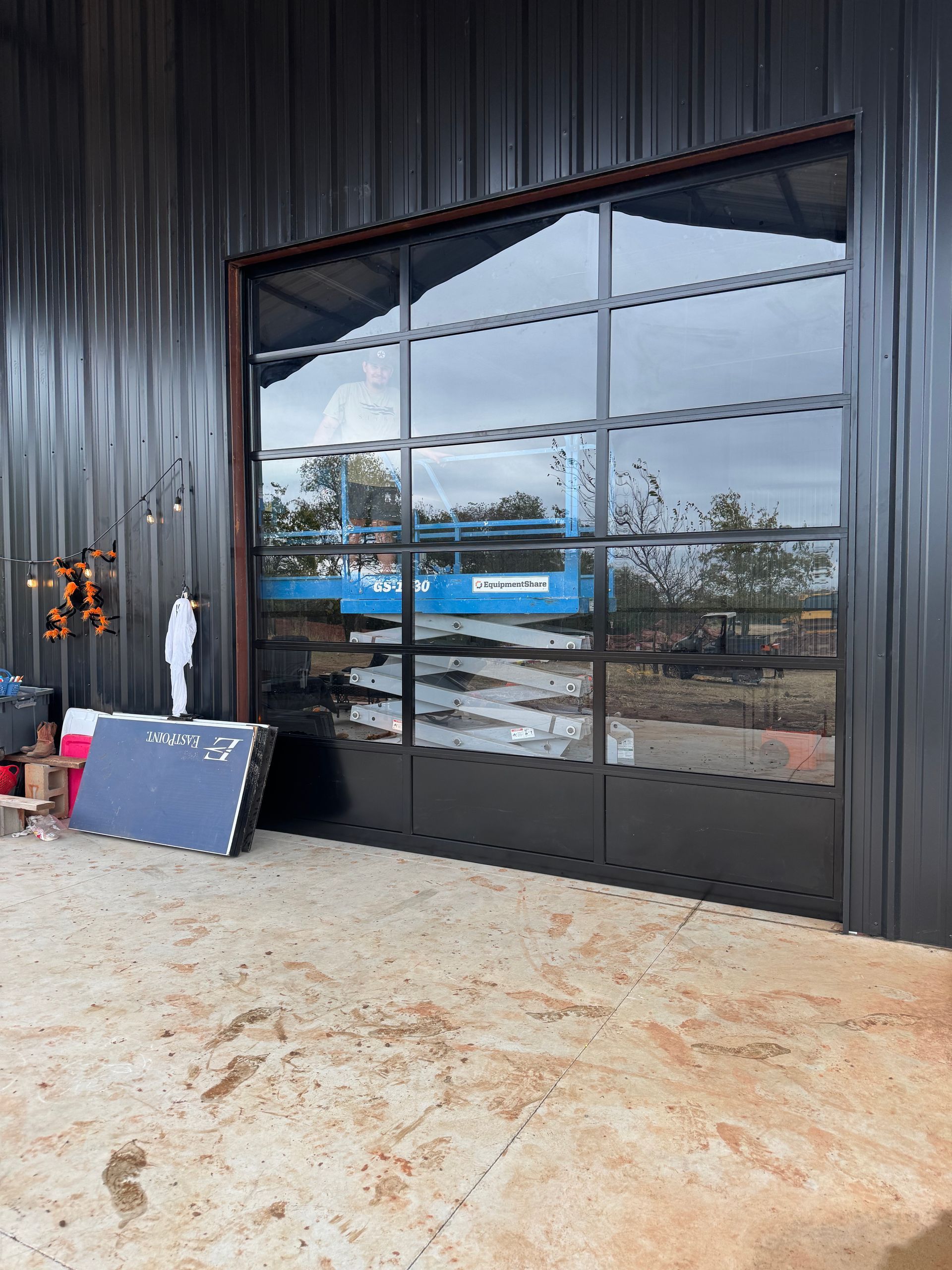 Black metal storefront with large reflective windows and a blue sign leaning by the entrance