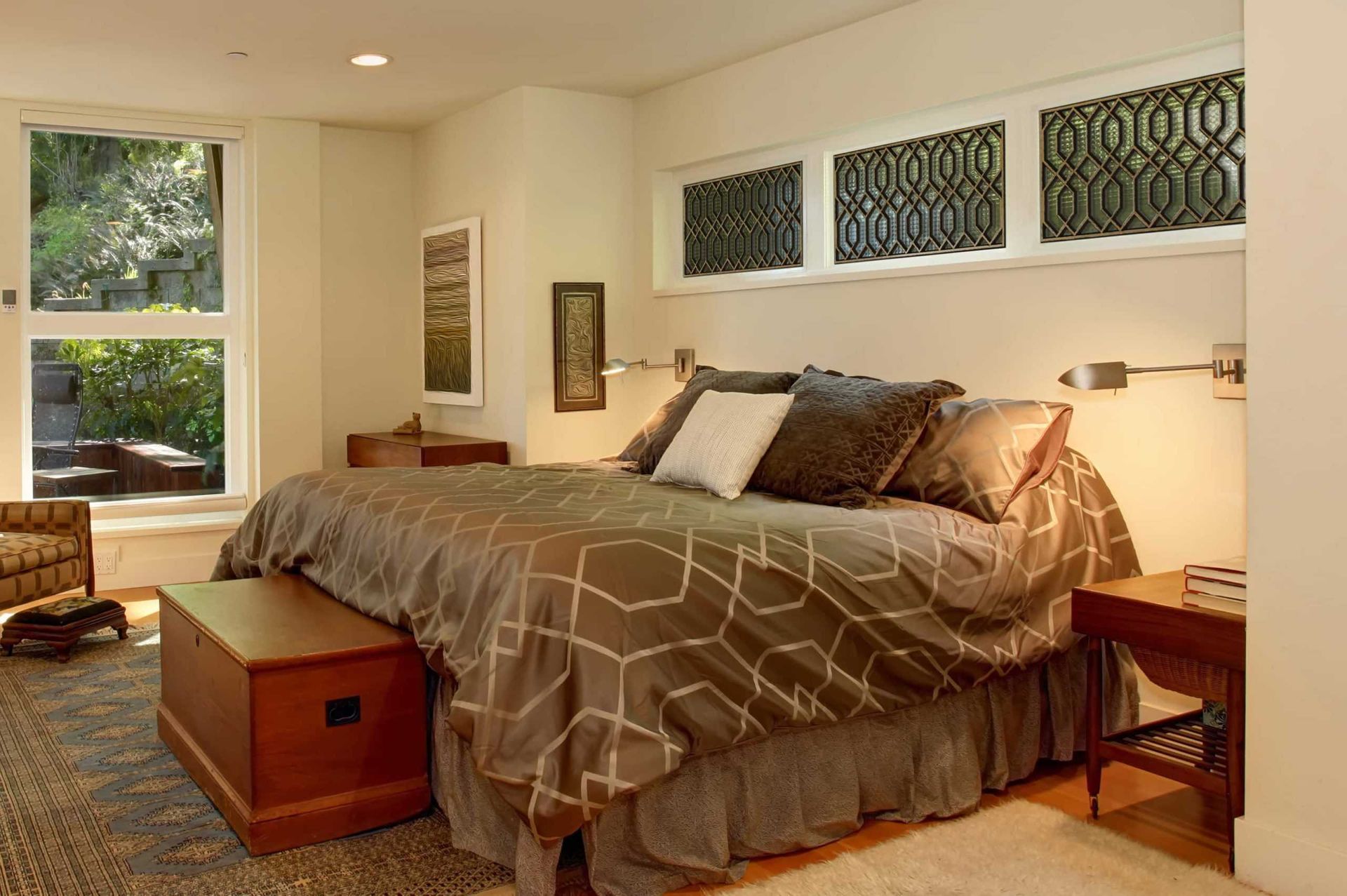 Cozy bedroom with a large bed, warm lighting, and windows letting in natural light