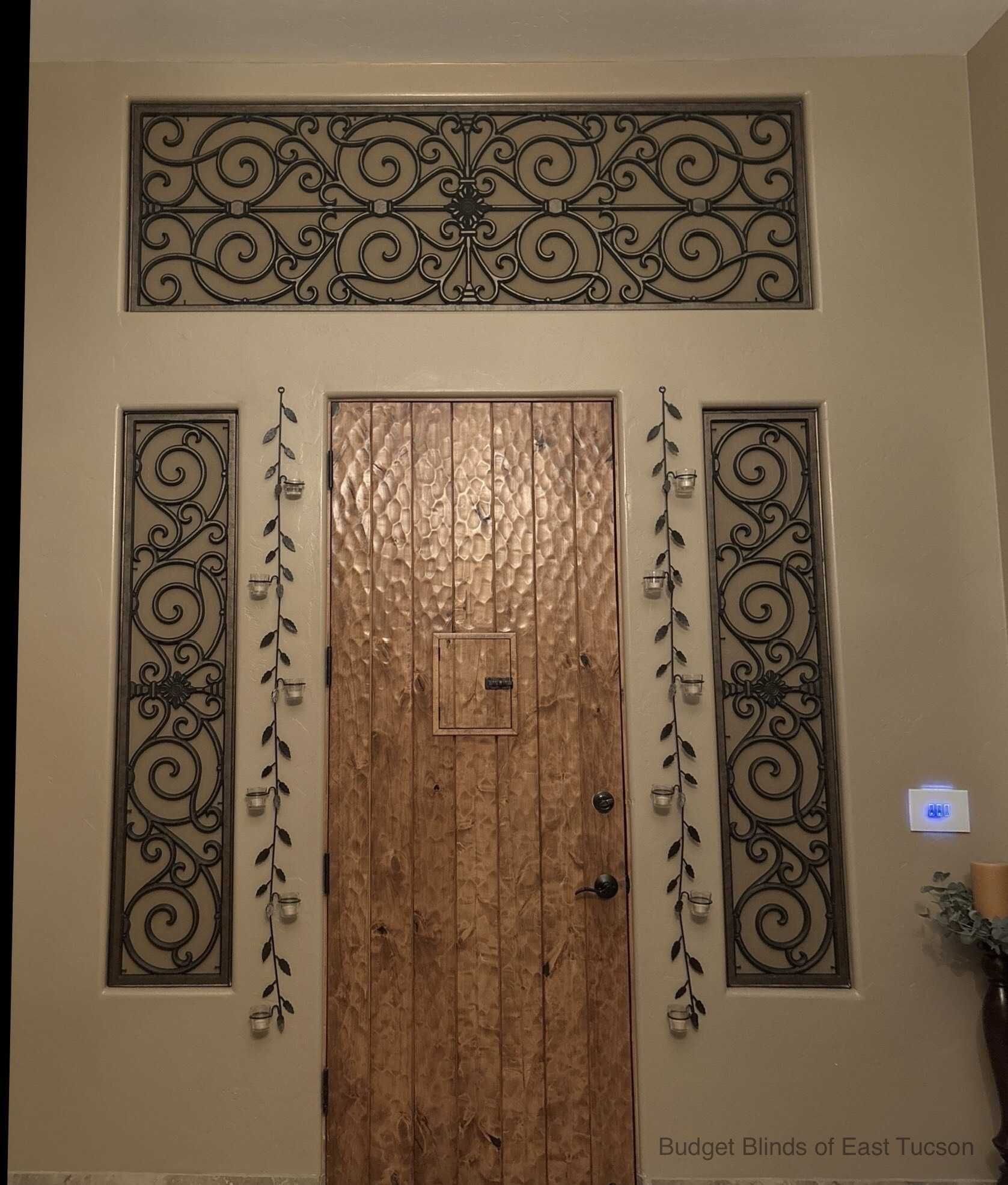 Decorative front door with ornate ironwork panels and a wall-mounted keypad beside it