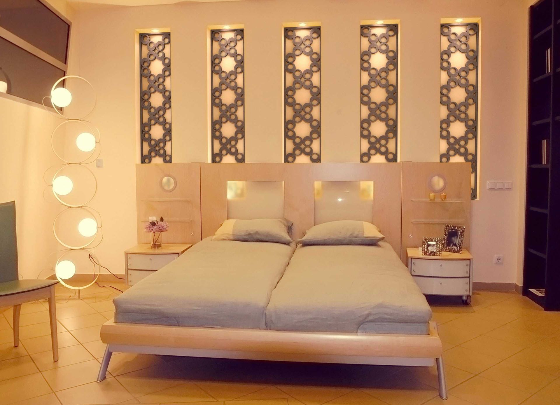 Modern bedroom with a double bed, warm lighting, and decorative patterned wall panels