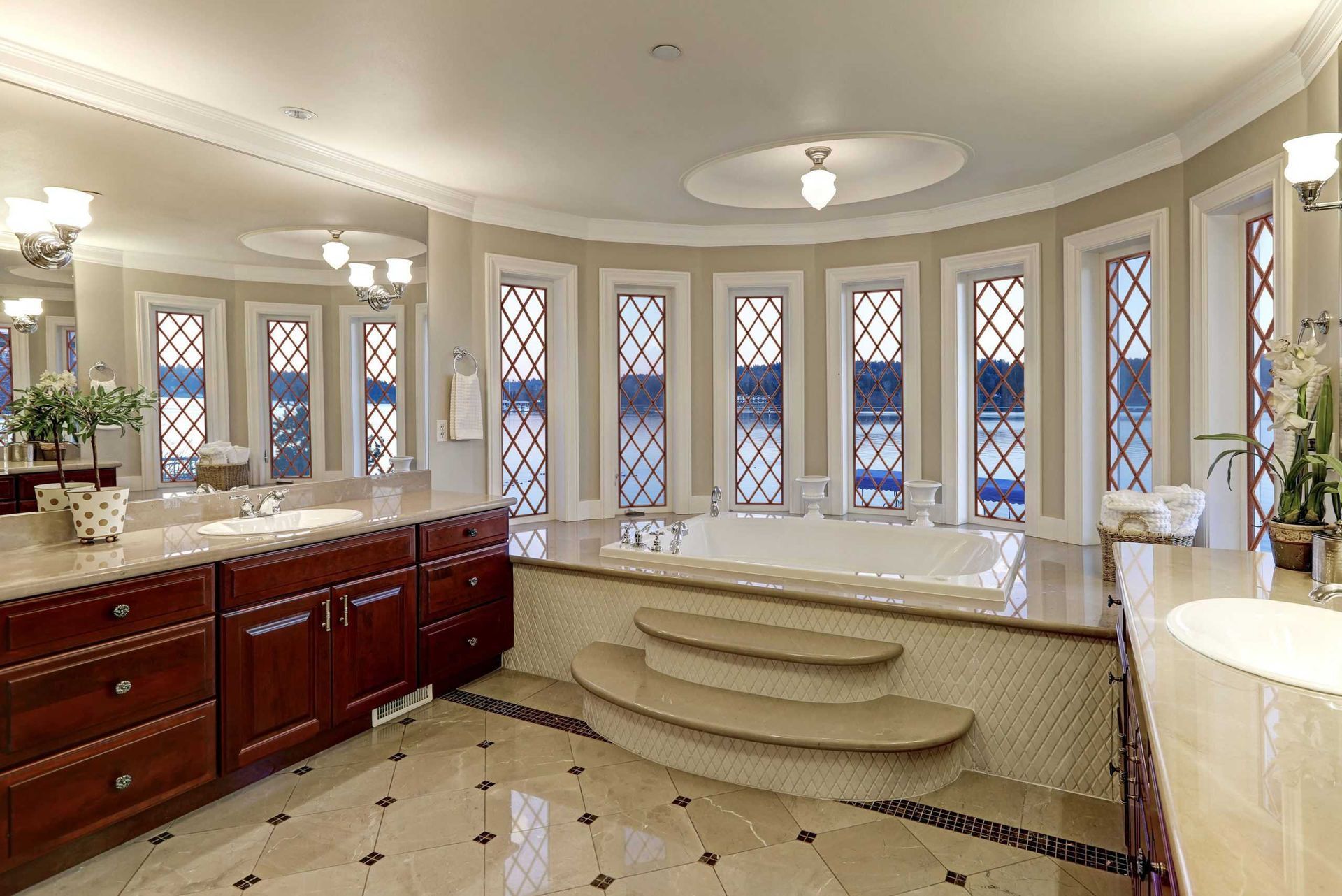 Elegant kitchen with curved island, granite counters, dark wood cabinets, and arched windows with Roman shades