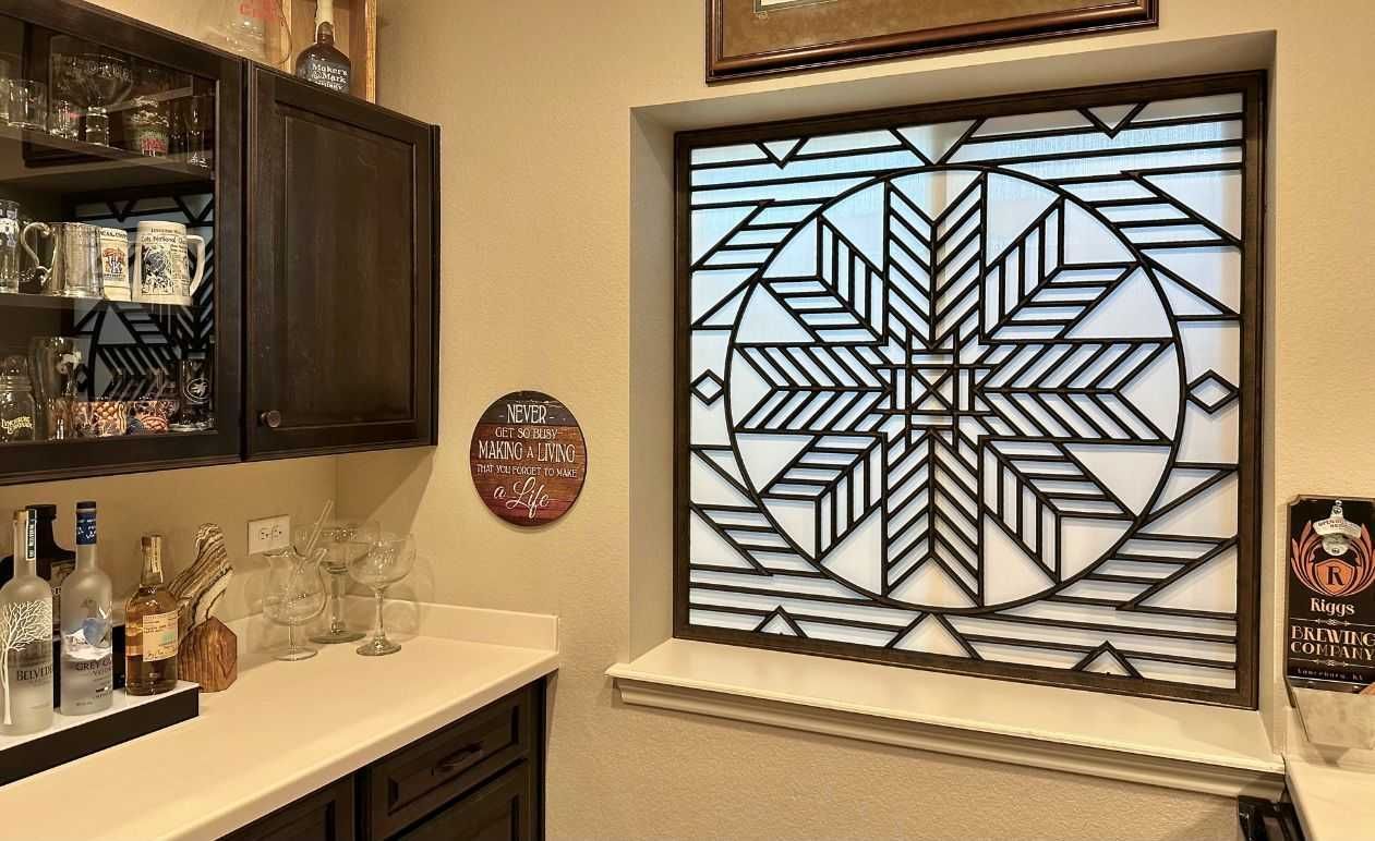 Kitchen counter with bottles and glass cabinet beside a window with geometric stained glass shades
