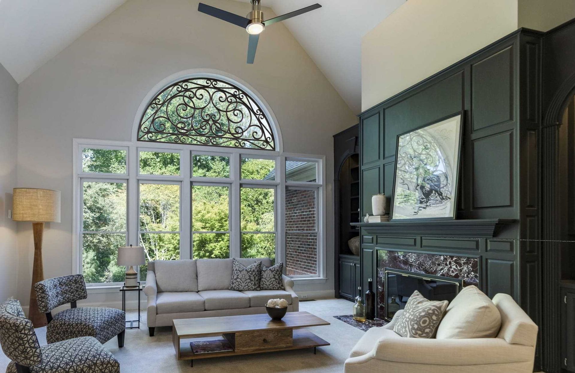 Elegant living room with arched window, dark built-ins, white sofa, and large decorative artwork