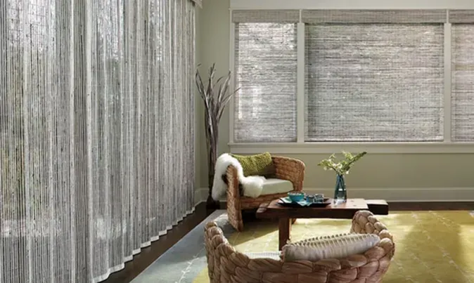 Living room with string curtains, woven chairs, and shades, with a small table.