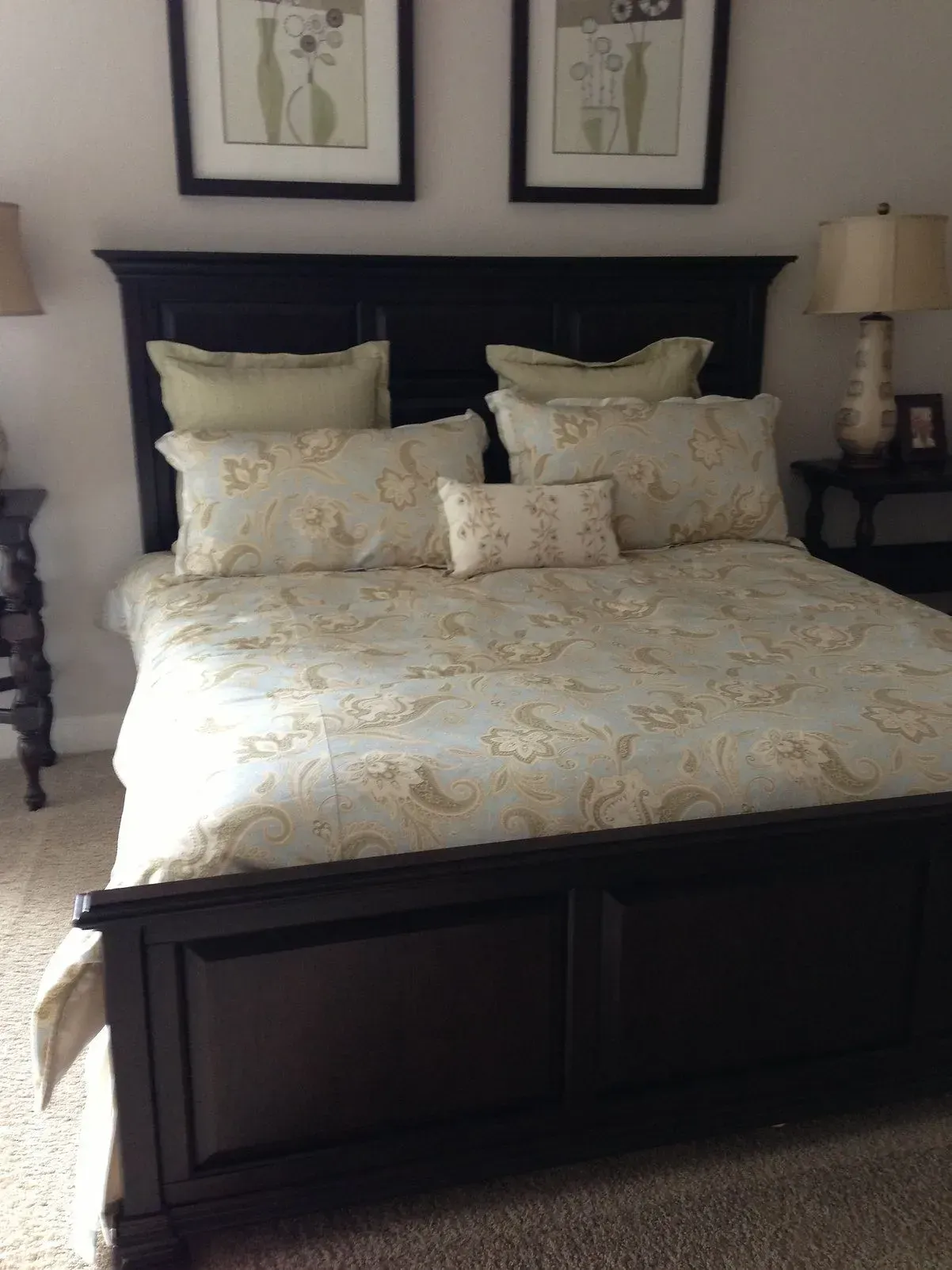 Dark wood bedroom set with patterned bedding and artwork.