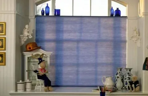 Blue and white window with blue jars, art pieces, and a toy.