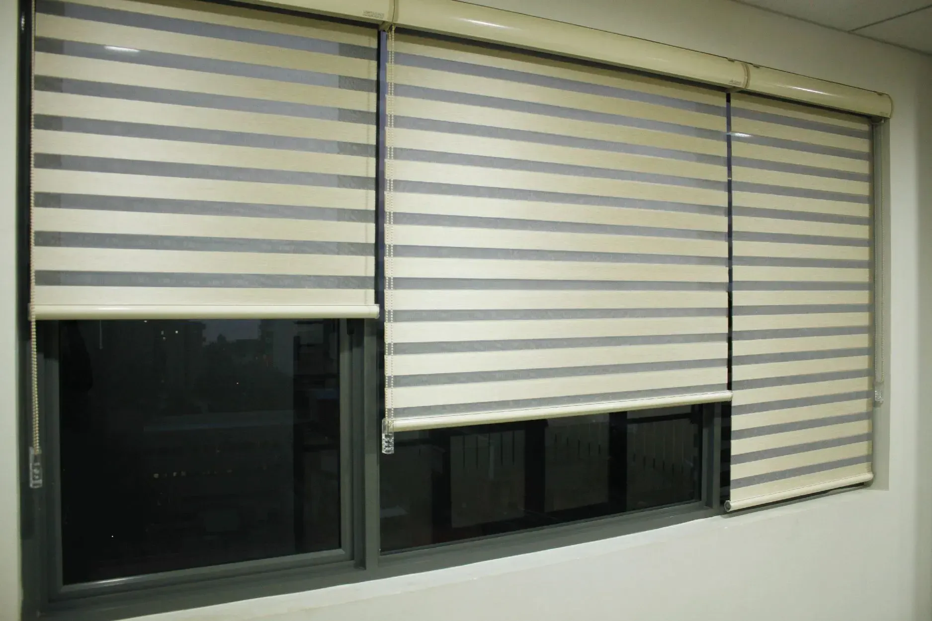 Window with three zebra blinds, alternating light and dark stripes, partially covering the window.
