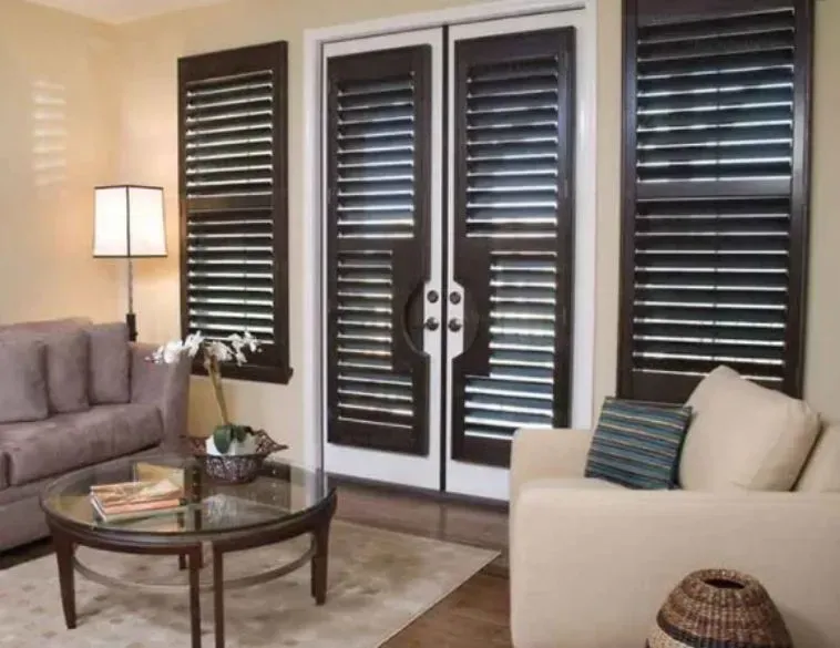 Living room with dark wood shutters, two sofas, a coffee table, and a floor lamp.