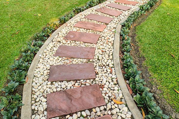 Stone path winding through a garden with brick pavers, pebbles, and greenery.