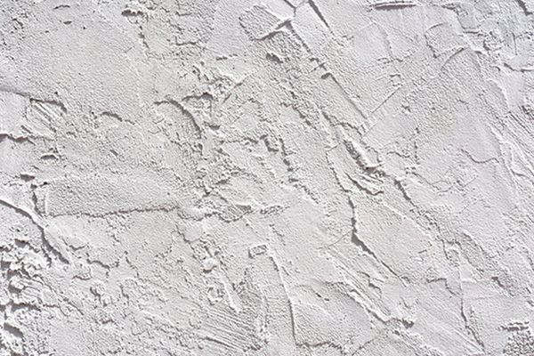Textured white stucco wall with uneven surface.