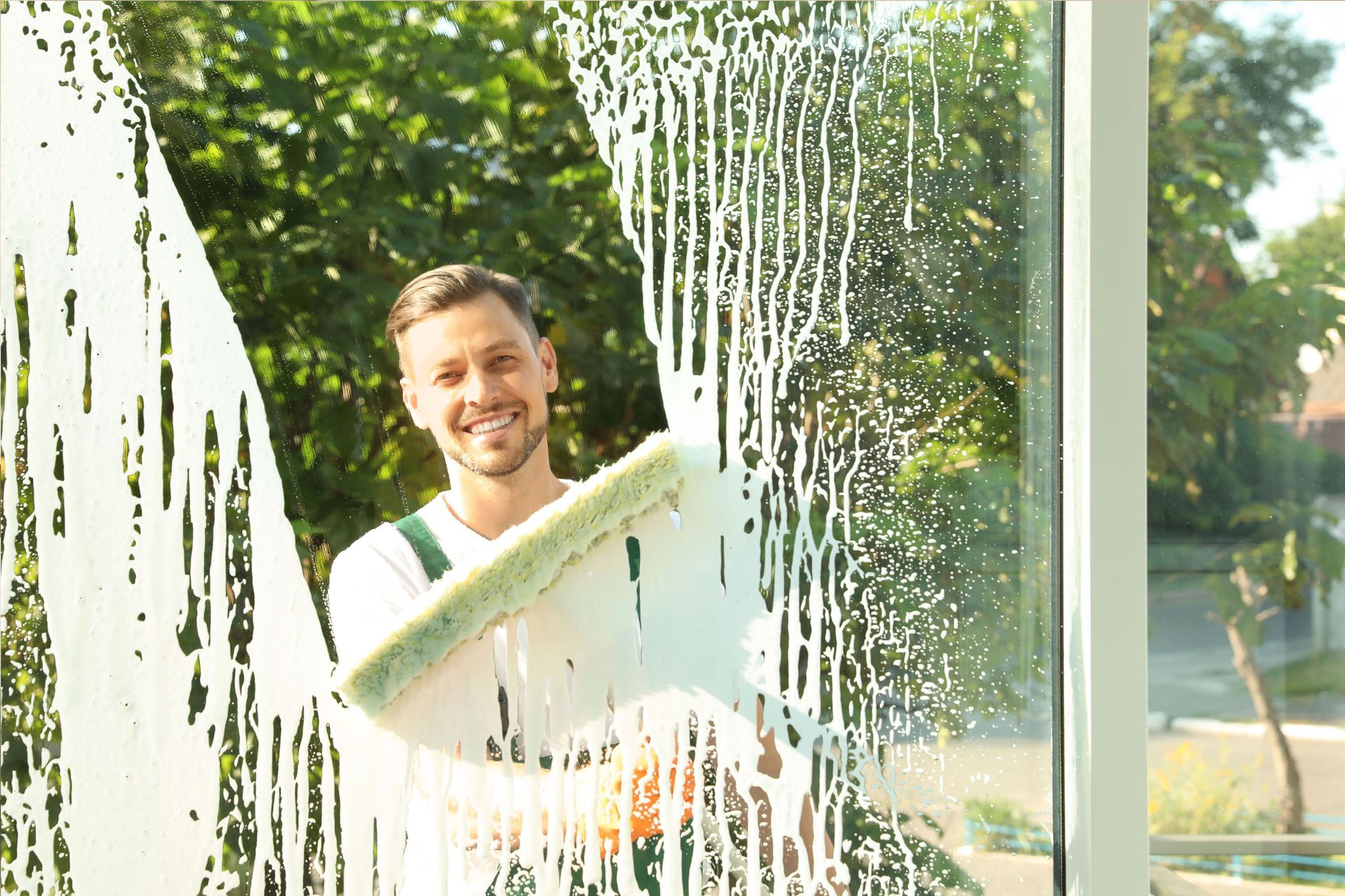 A man is cleaning a window with a sponge.