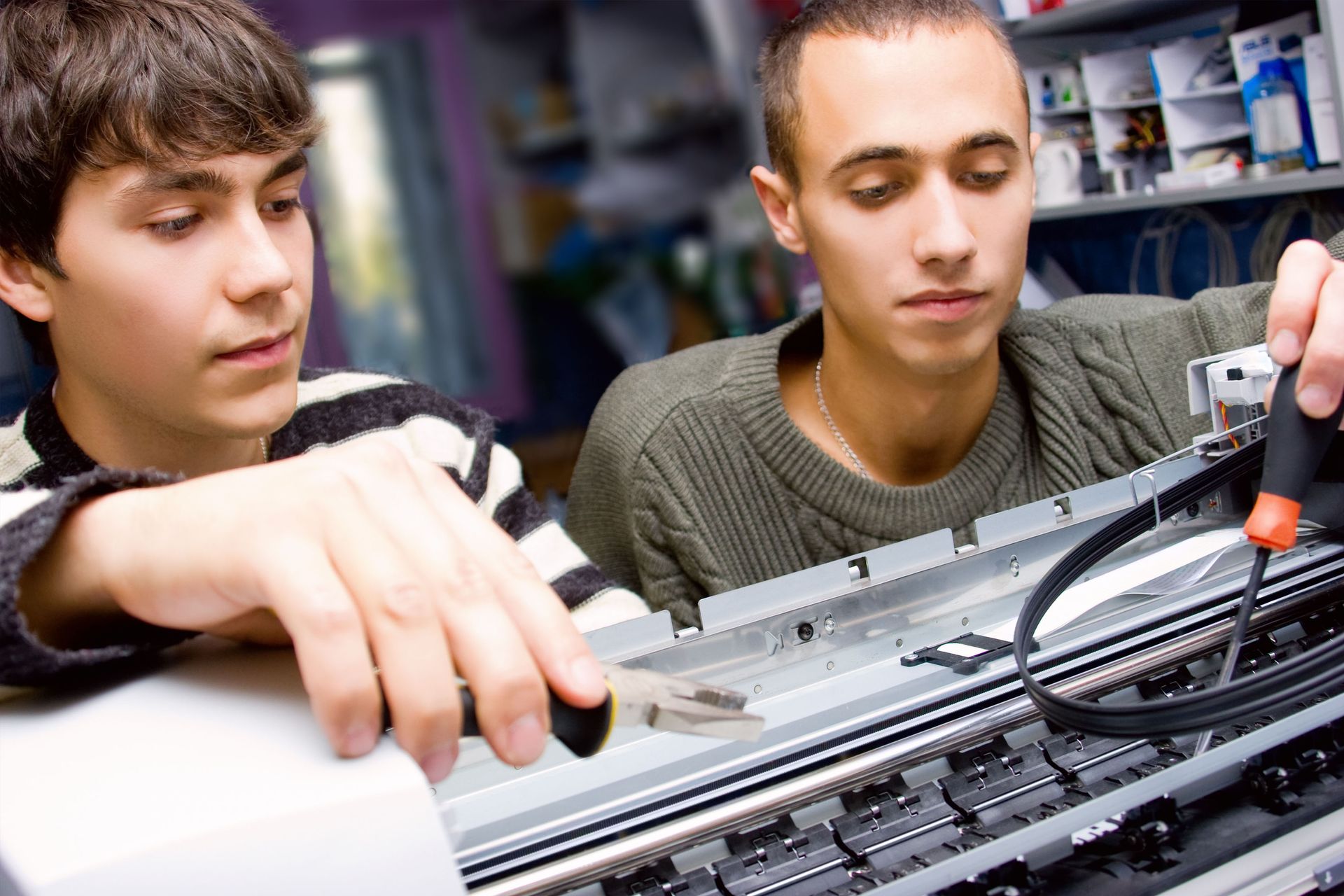 Two young men are working on a printer in a store.