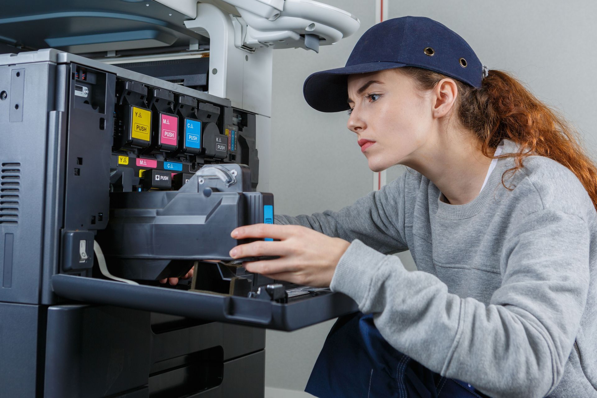 A woman in a hat is fixing a printer.