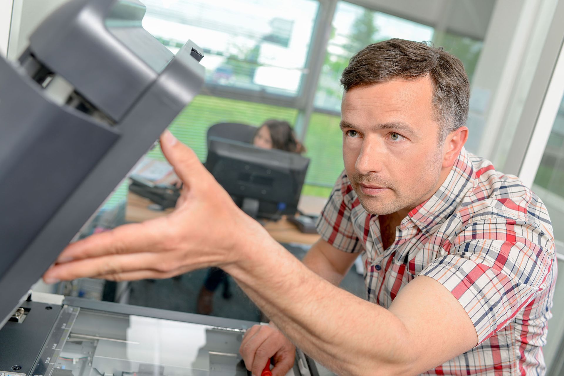 A man is fixing a printer in an office