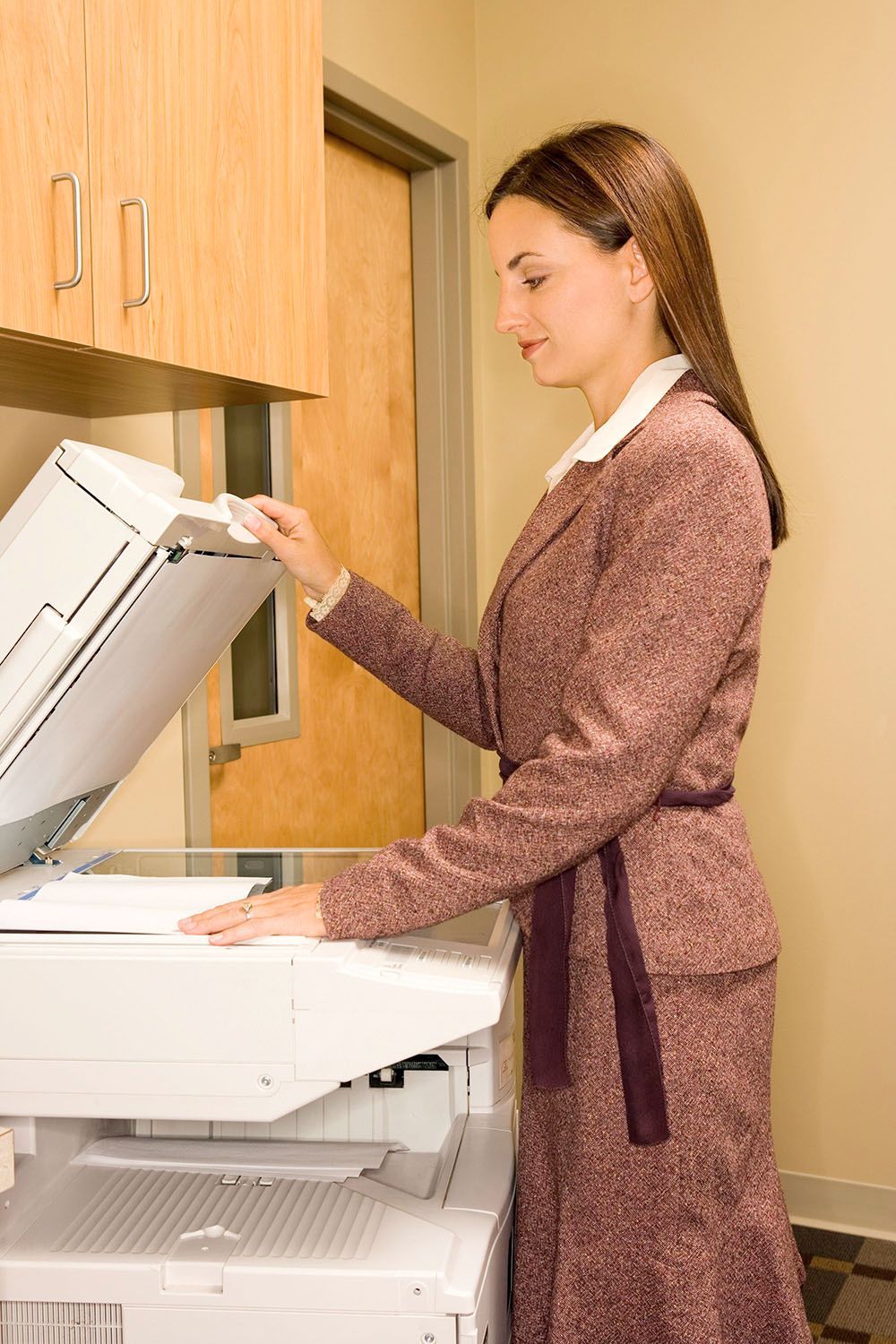 A woman in a suit is using a photocopier