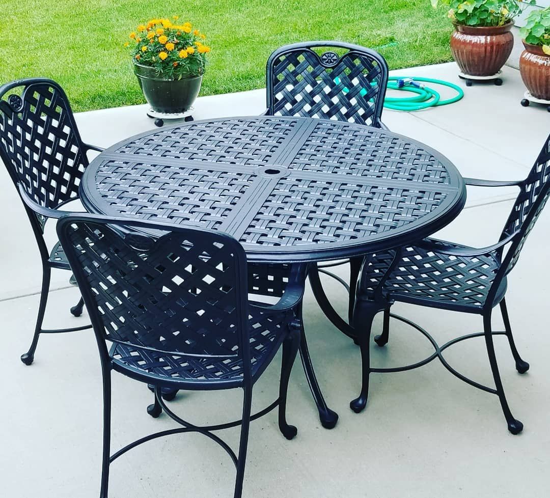 A table and chairs on a patio with potted plants in the background