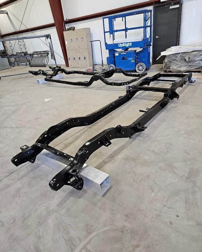 A car frame is sitting on a concrete floor in a garage.