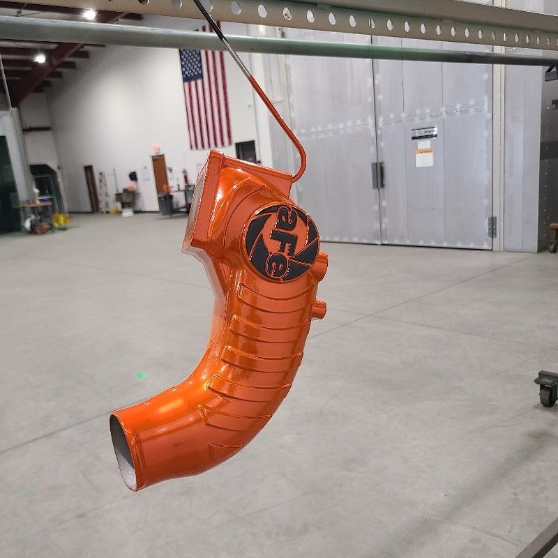 An orange pipe with a logo on it is hanging from a metal bar