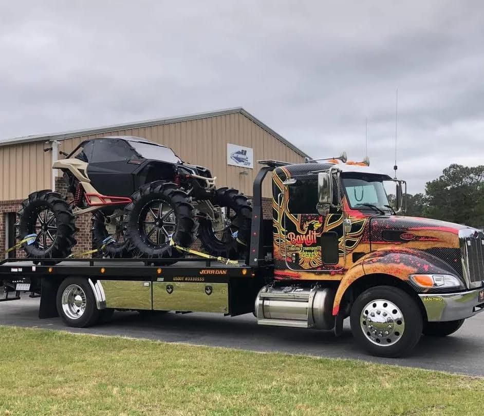A tow truck with a car and tires on the back is parked in front of a building.