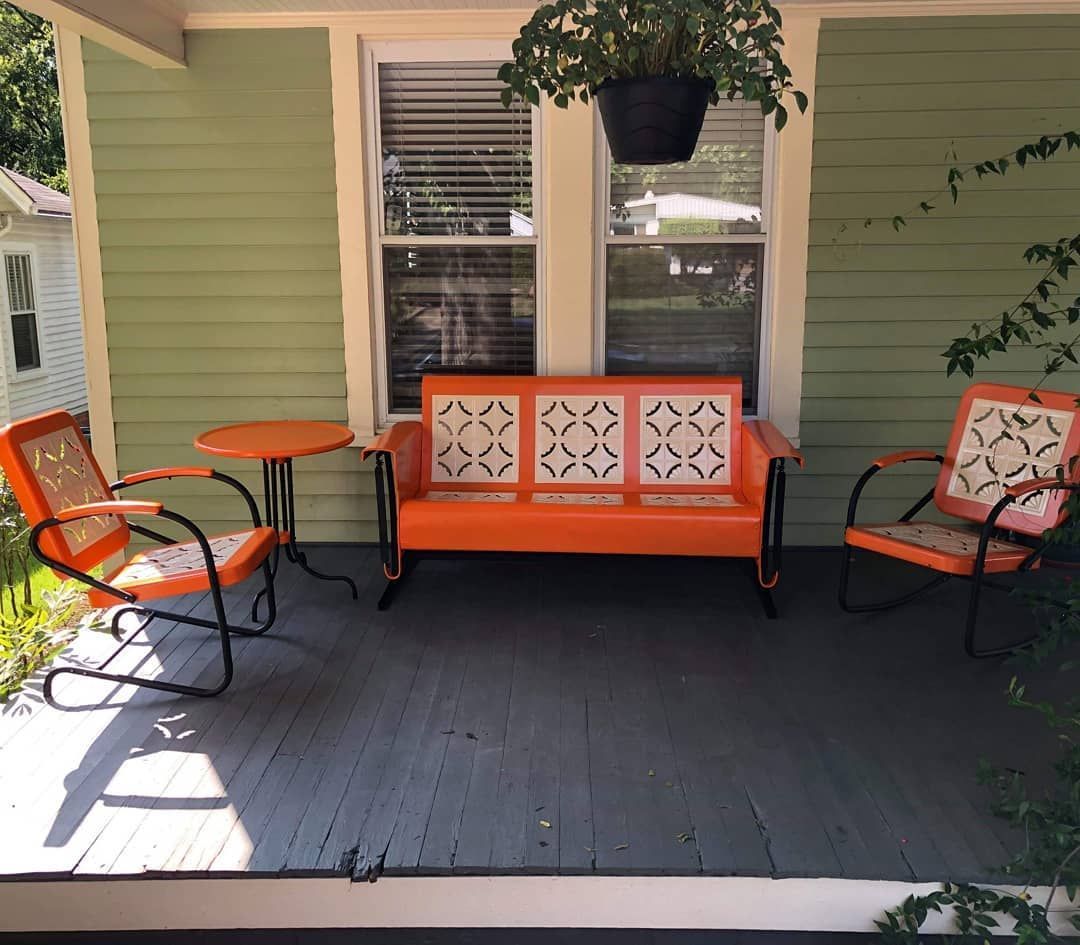A porch with an orange couch and two chairs