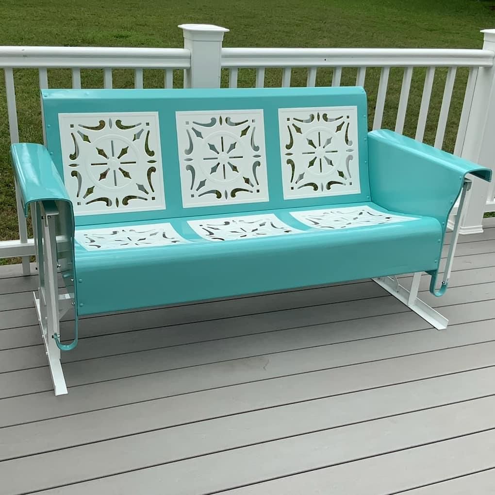 A blue and white rocking bench on a deck