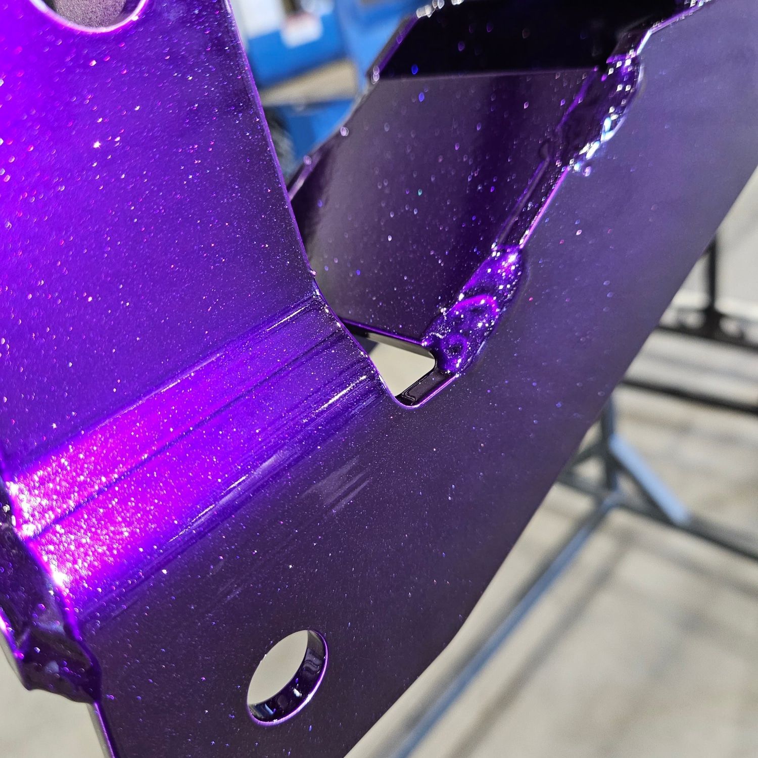 A close up of a purple metal piece with a hole in it