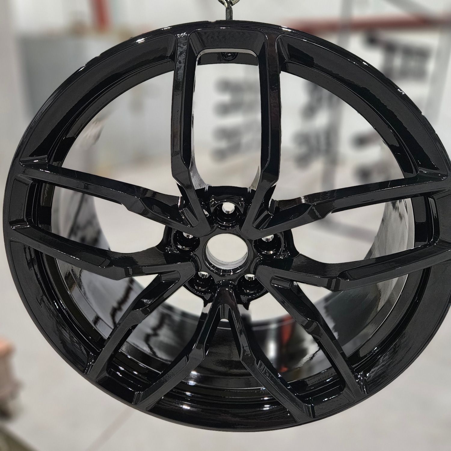 A close up of a black car wheel hanging from a chain.