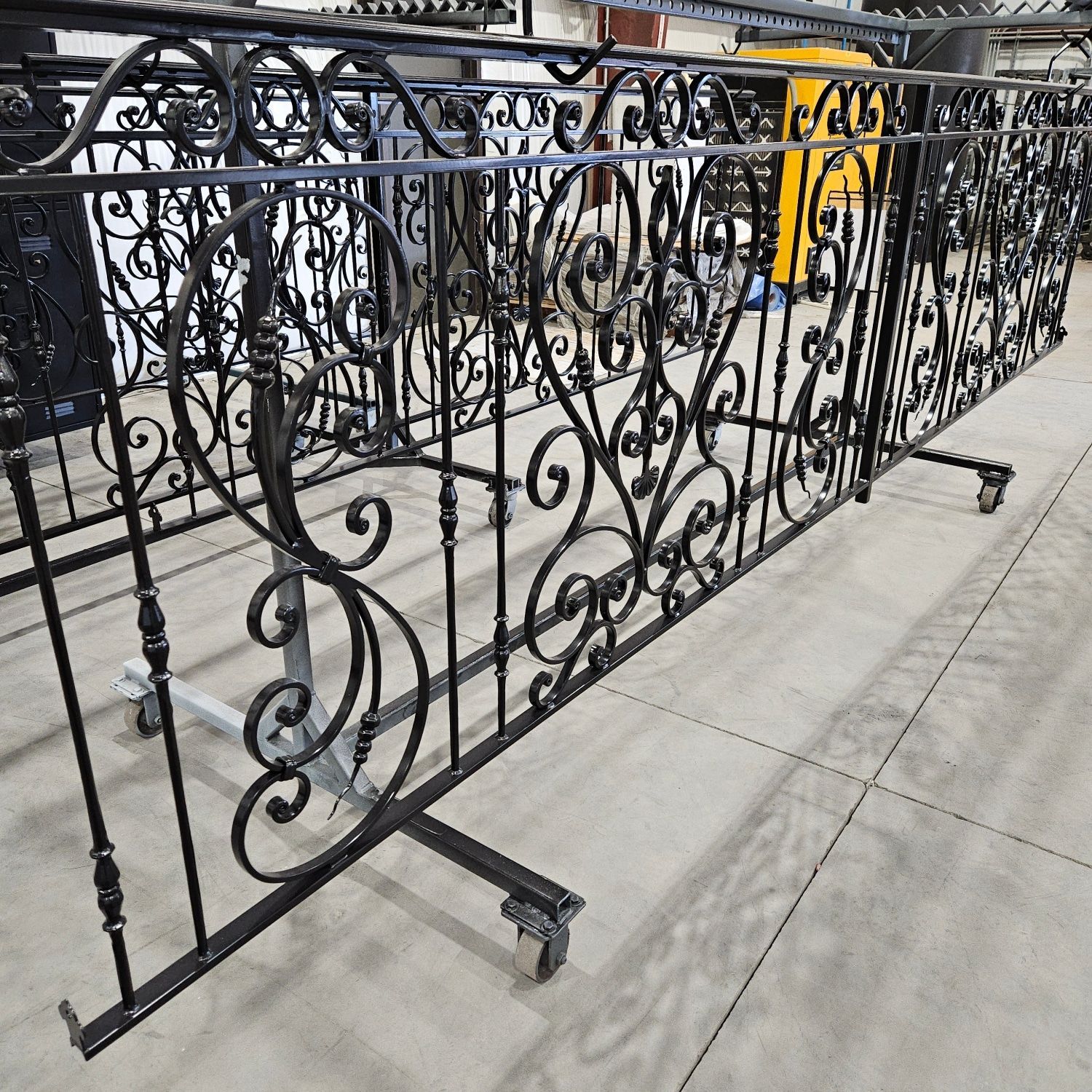 A row of wrought iron fences are sitting on a concrete floor