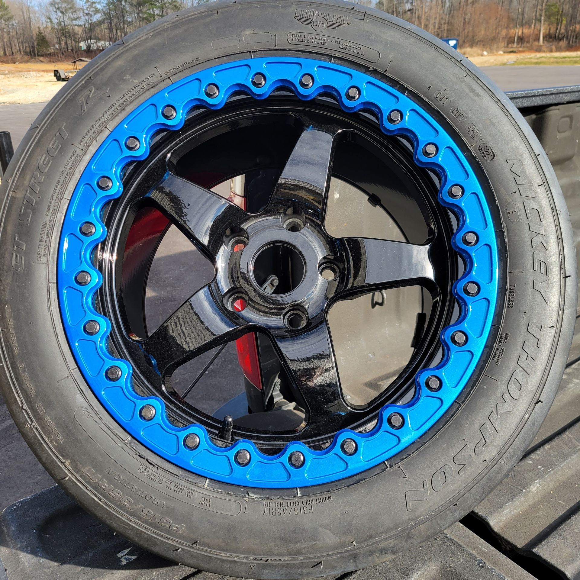 A black tire with a blue rim is sitting on a truck bed